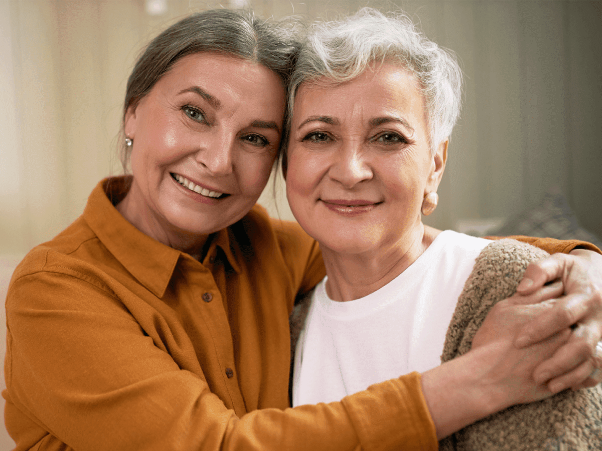 Two women are hugging and smiling for a picture.