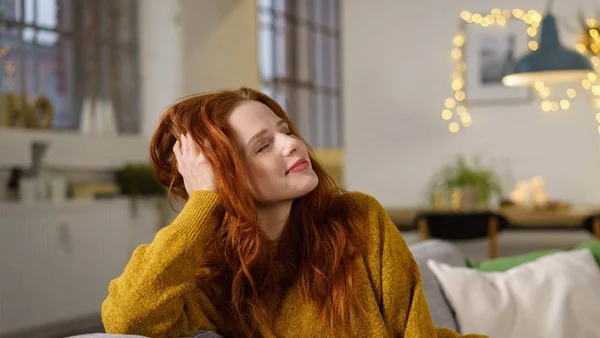 A woman with red hair sitting on the couch